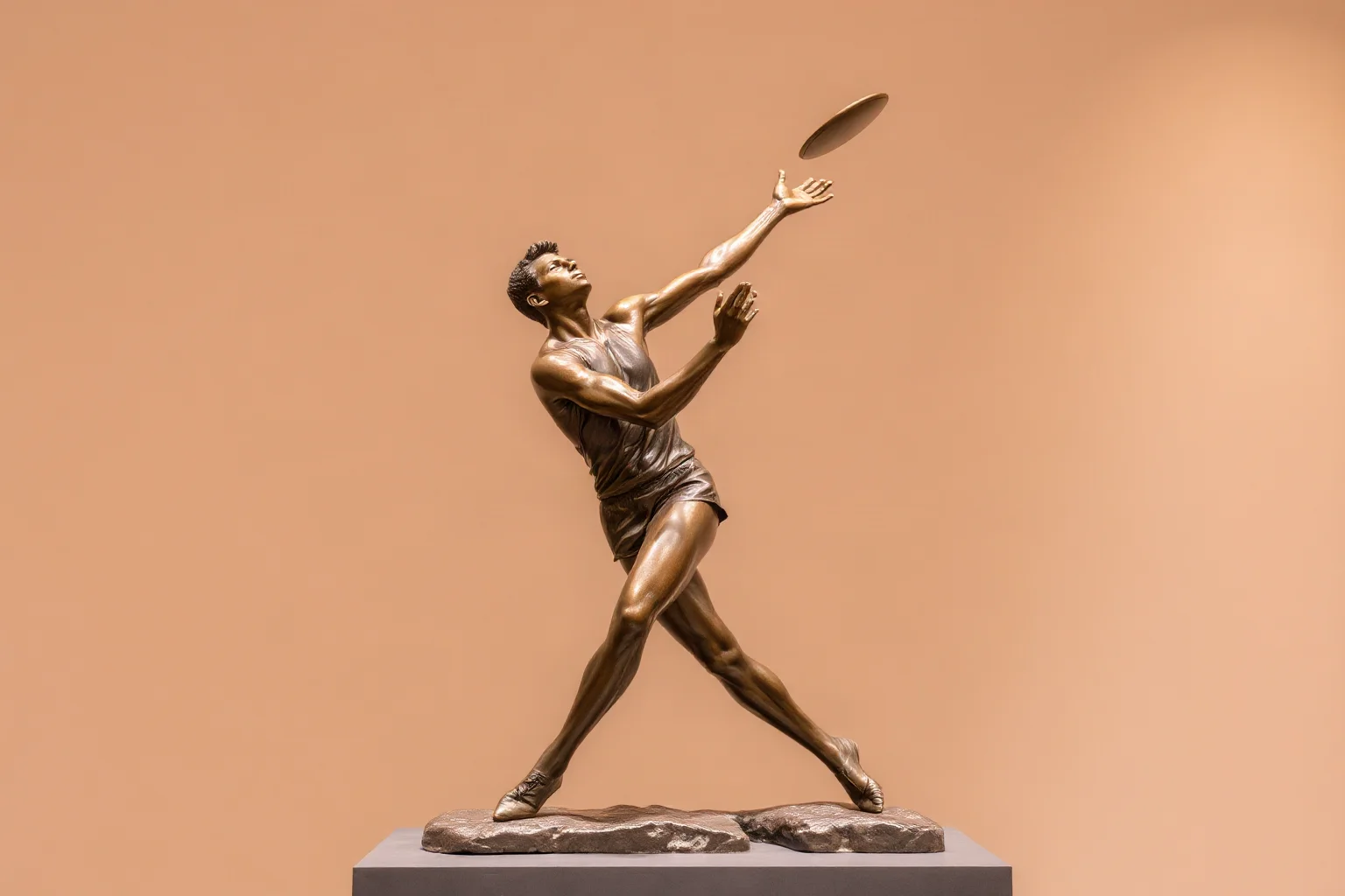 A bronze sculpture of an athlete mid-motion throwing a discus, dynamic pose, plain gallery background