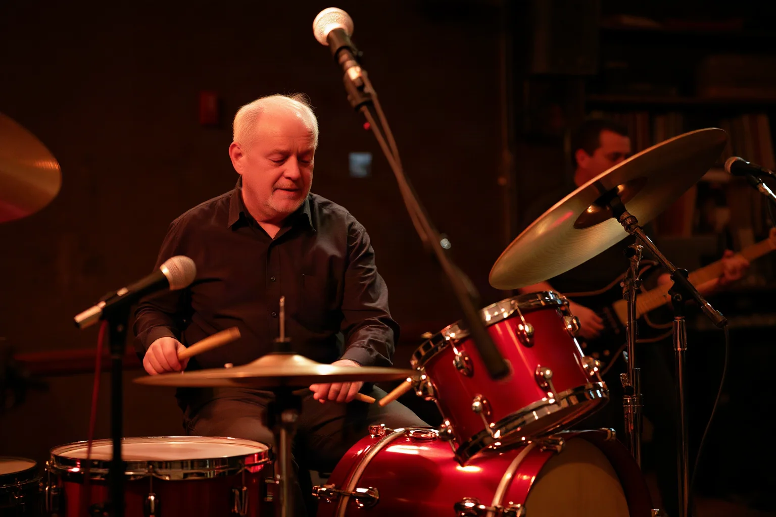 A calm, seasoned drummer with a vintage kit playing with subtle precision in a smoky blues-rock club