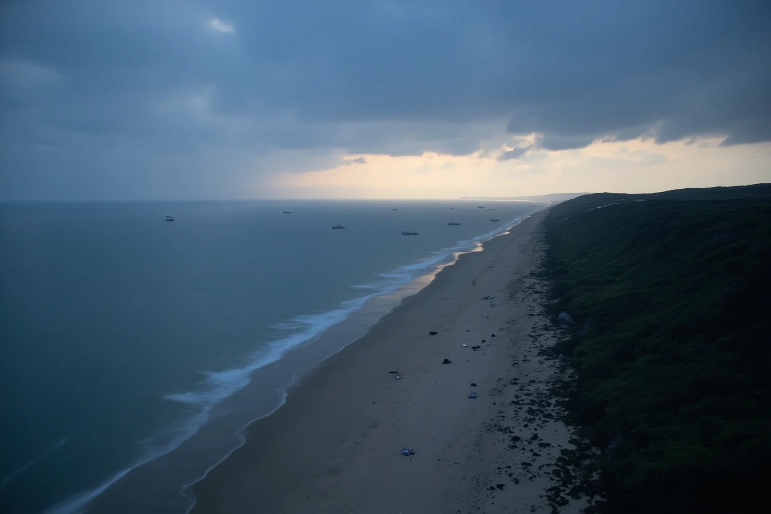 A cloudy English Channel coast at dawn with a fleet of landing craft approaching a beach