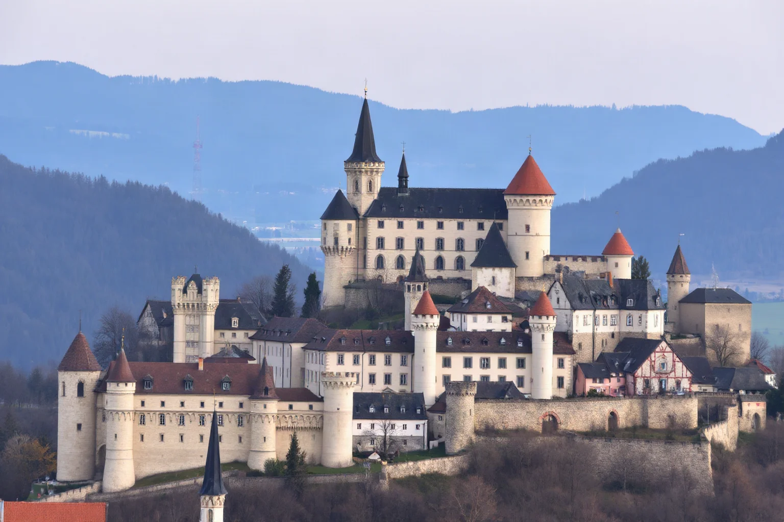 A cluster of medieval European castles and walled towns across a hilly Central European landscape