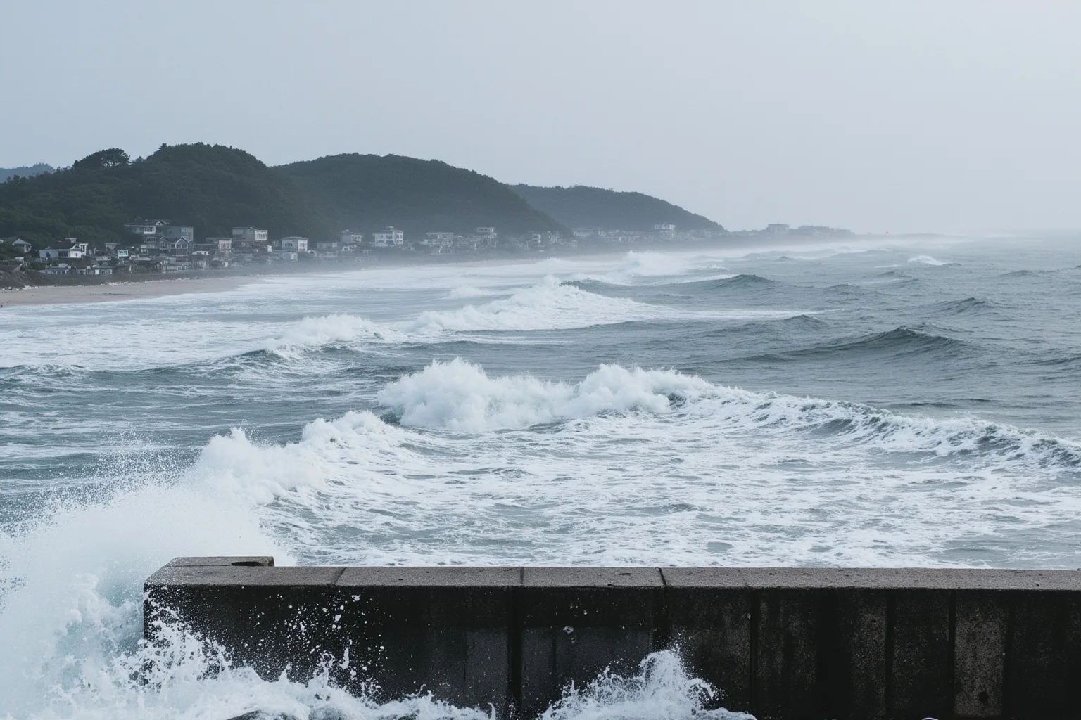 A coastal Japanese fishing town overwhelmed by a massive tsunami wave with a seawall in the foreground