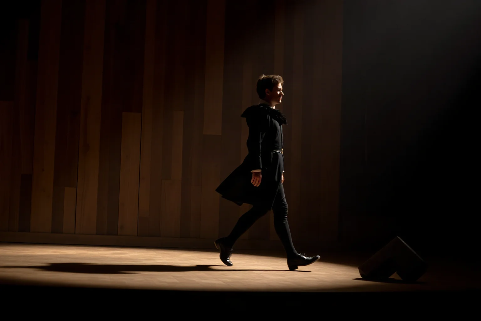 A confident Elizabethan-era figure strutting across a wooden stage in silhouette, representing the word 'Swagger'