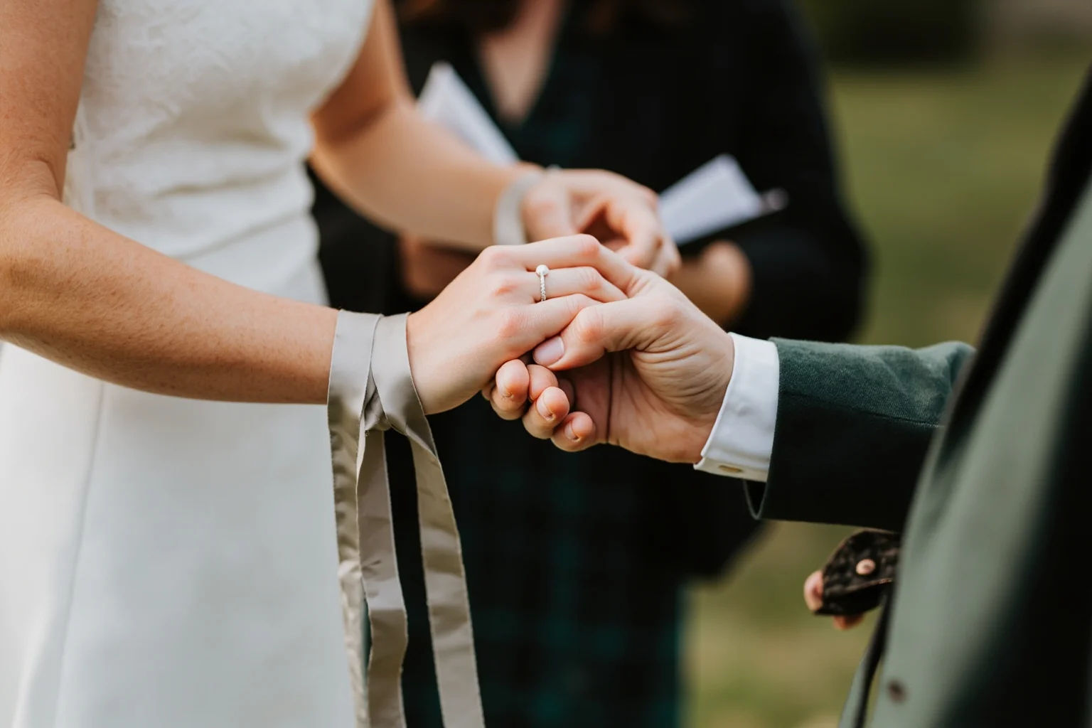 A couple's hands bound together with ribbon during an outdoor Celtic-style wedding ceremony