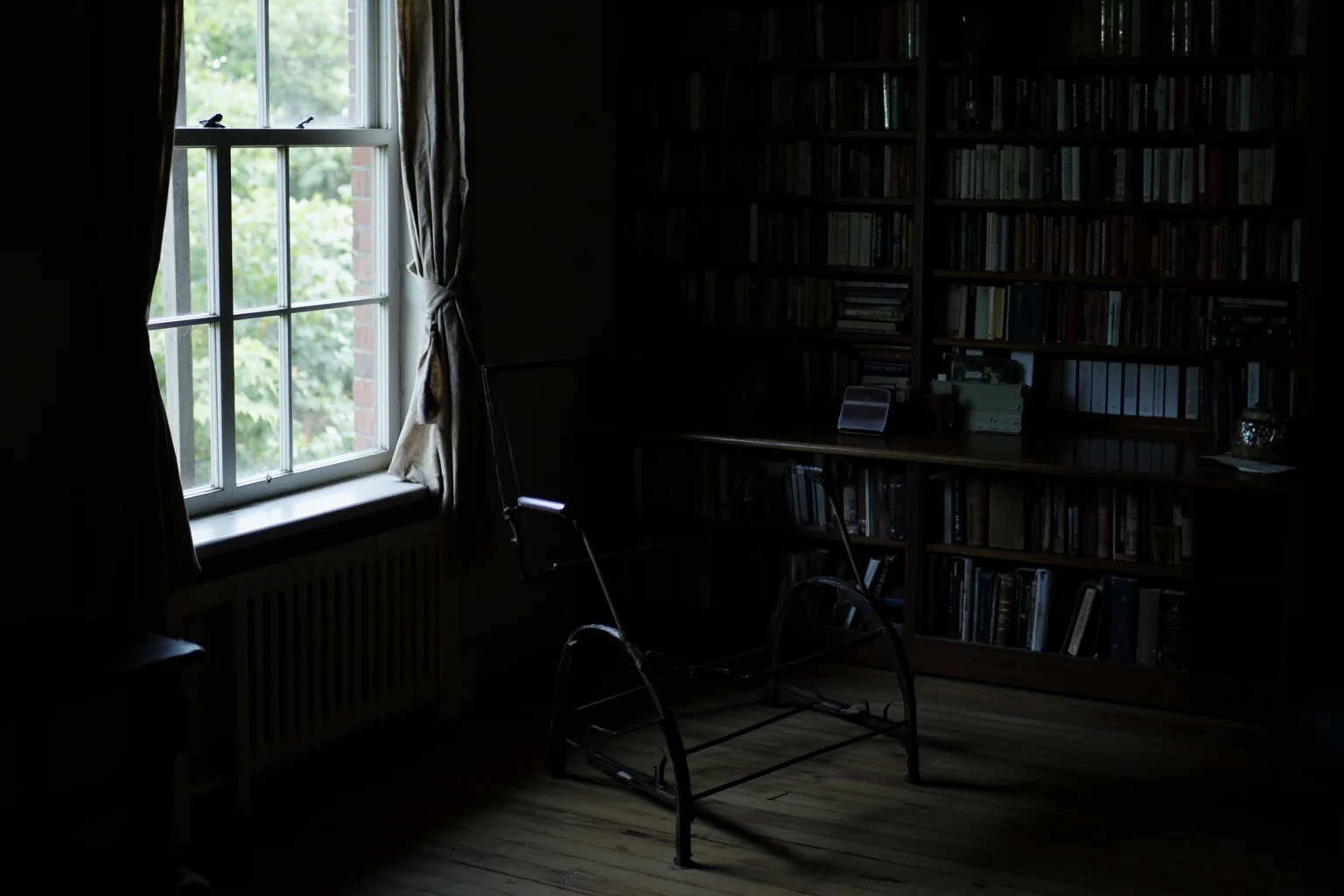 20 of the Most Mysterious People in History 15 A dim, book-lined study with an empty writing chair and drawn curtains, suggesting a reclusive absent author