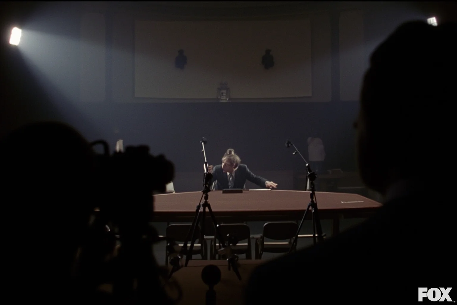 Most Important Historical Events Televised Live 6 A dimly lit 1970s Senate hearing room with cameras and microphones pointed at an empty witness table, TV lights glowing