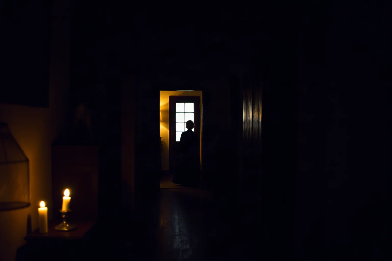 A faint ghostly female silhouette in old plantation-era clothing standing in a dim candlelit colonial house hallway