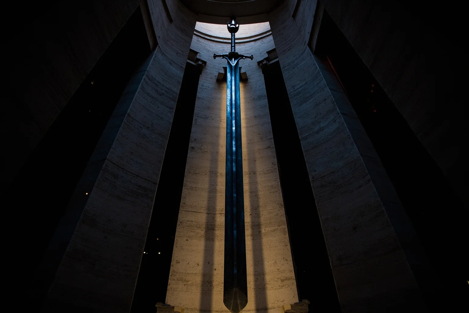 A giant ceremonial sword displayed inside a stone monument tower, dramatic lighting