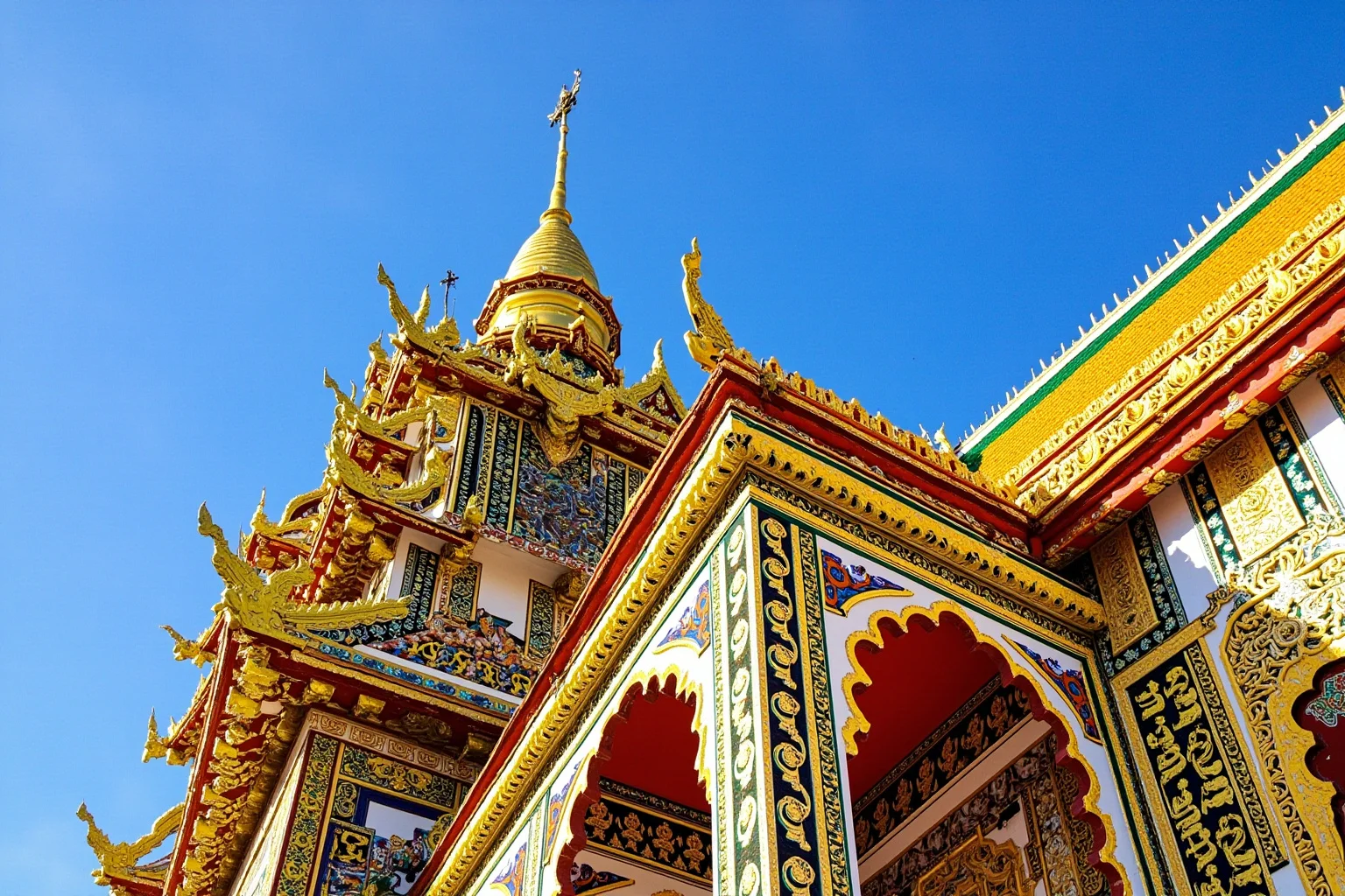 A gold-spired temple building with intricate colorful mosaic tilework