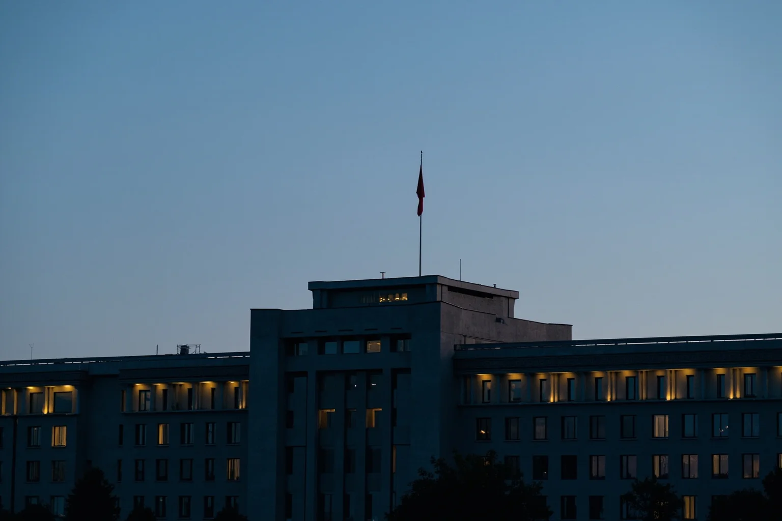 Empires That Fell Slowly—and 20 That Collapsed Overnight 20 A grey Soviet-era government building with a lowered red flag at dusk