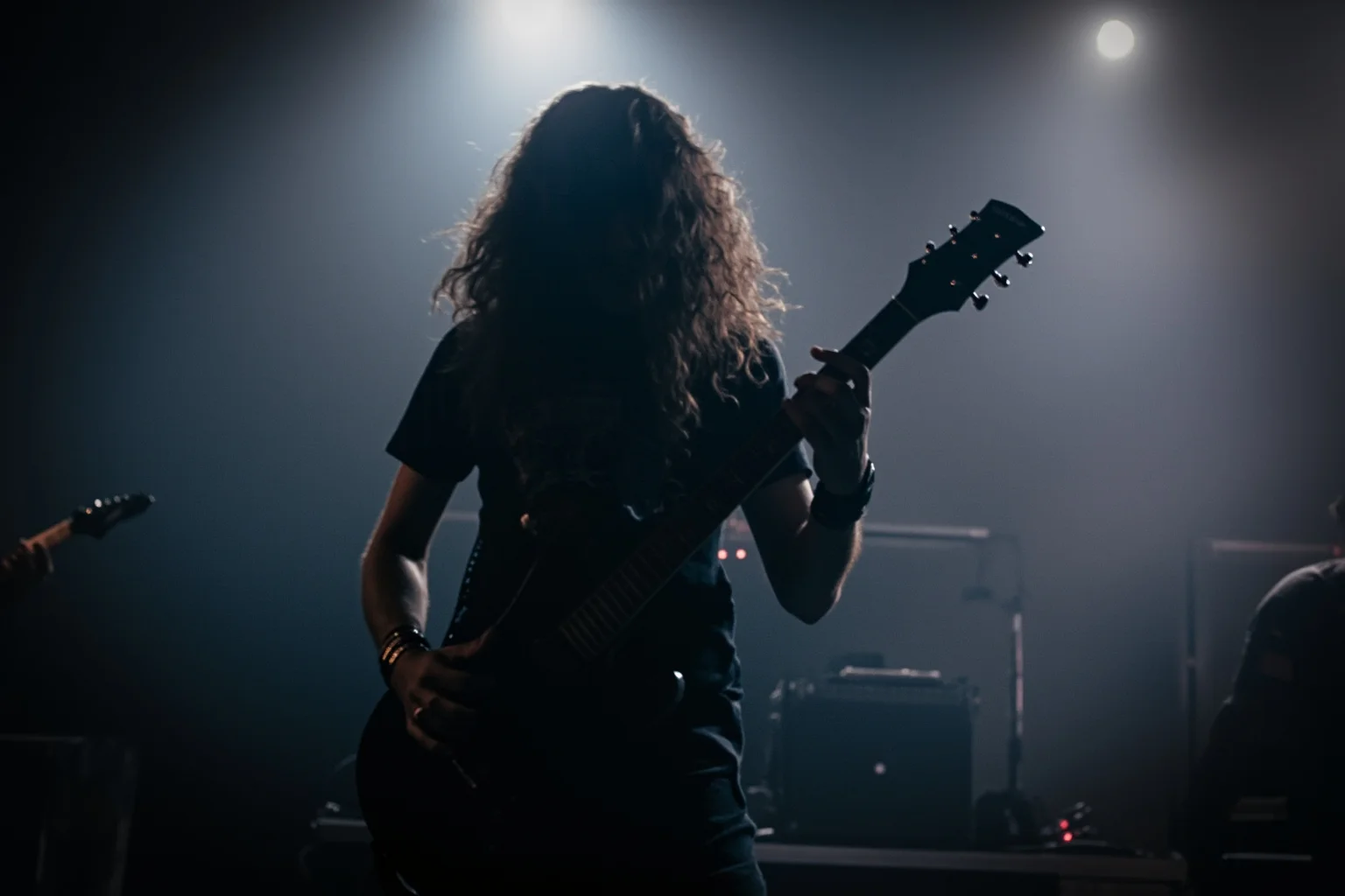 A heavy metal guitarist playing a down-tuned electric guitar with dark, ominous stage fog and low lighting