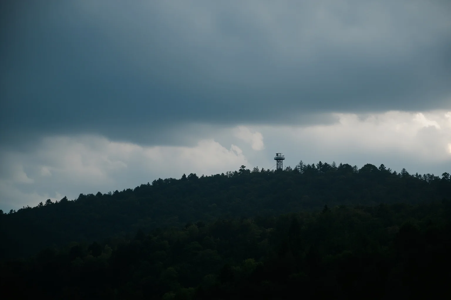 The Human Lightning Rod: The Man Who Was Struck Seven Times 3 A lone fire lookout tower on a forested mountain ridge with dark storm clouds gathering overhead