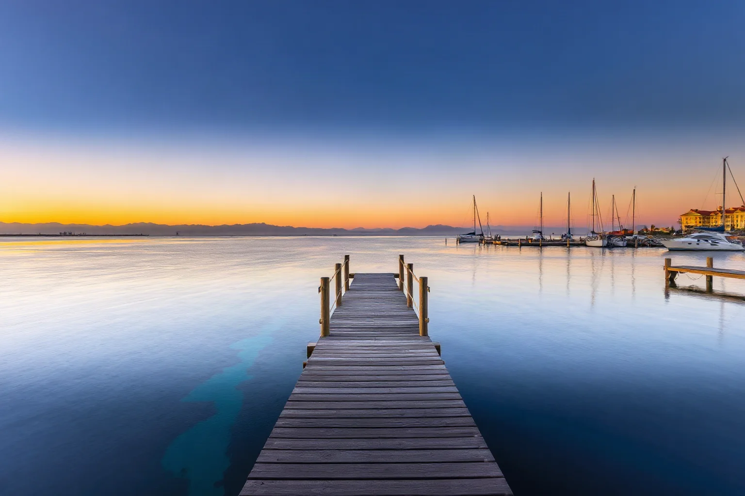 A lone wooden dock at sunset overlooking a calm Pacific-theater harbor