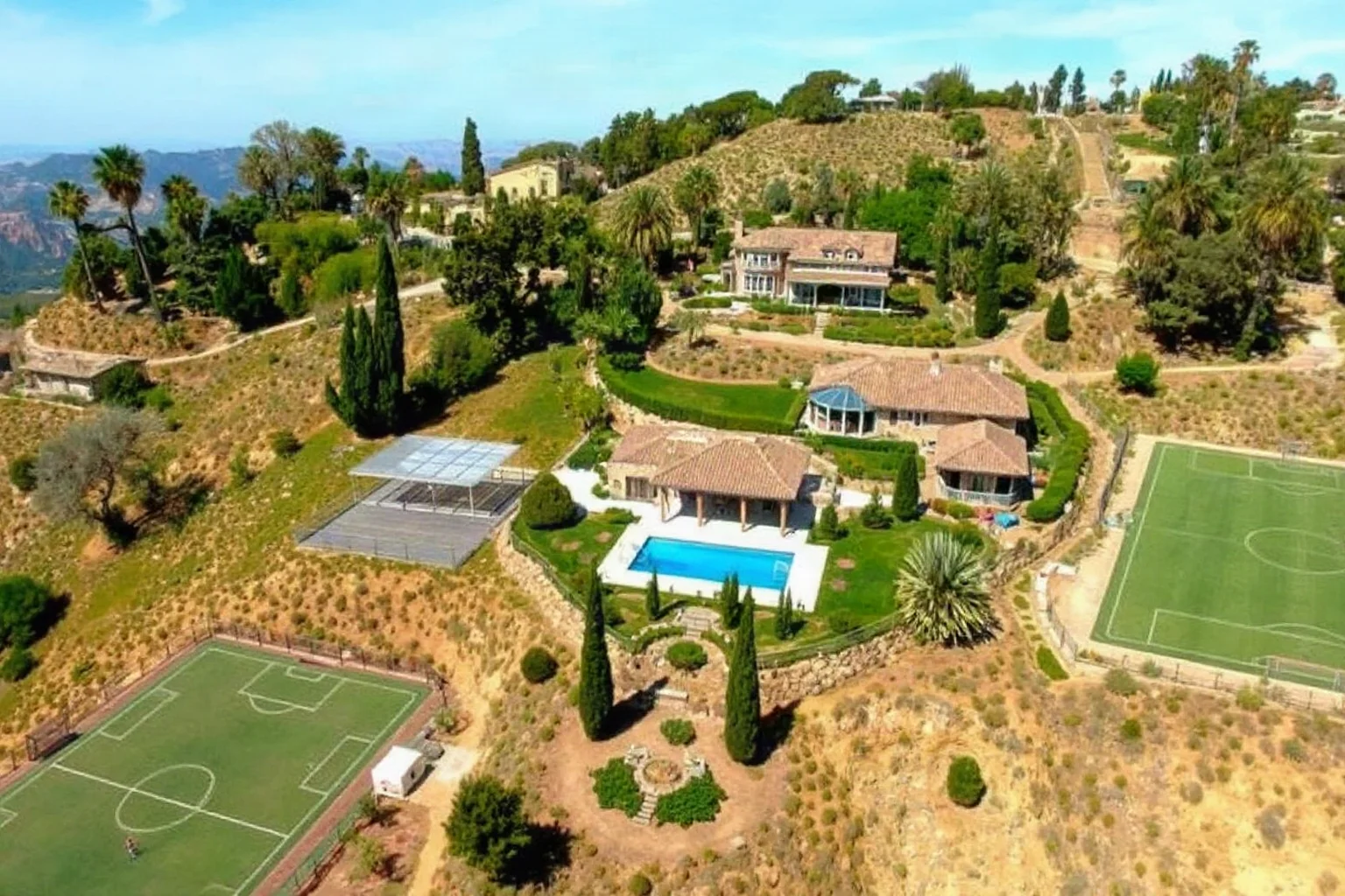 A luxurious hillside compound with a soccer field and pool, symbolizing an unusually comfortable private prison