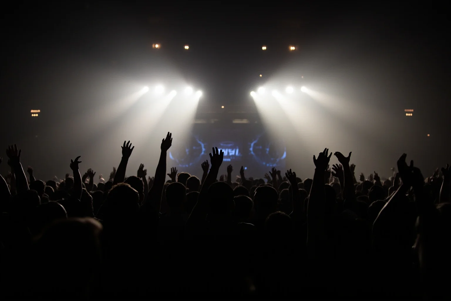 Incredible Facts About the Beatles' Greatest Band History 10 A massive stadium crowd silhouette with hands raised toward a distant stage under bright lights