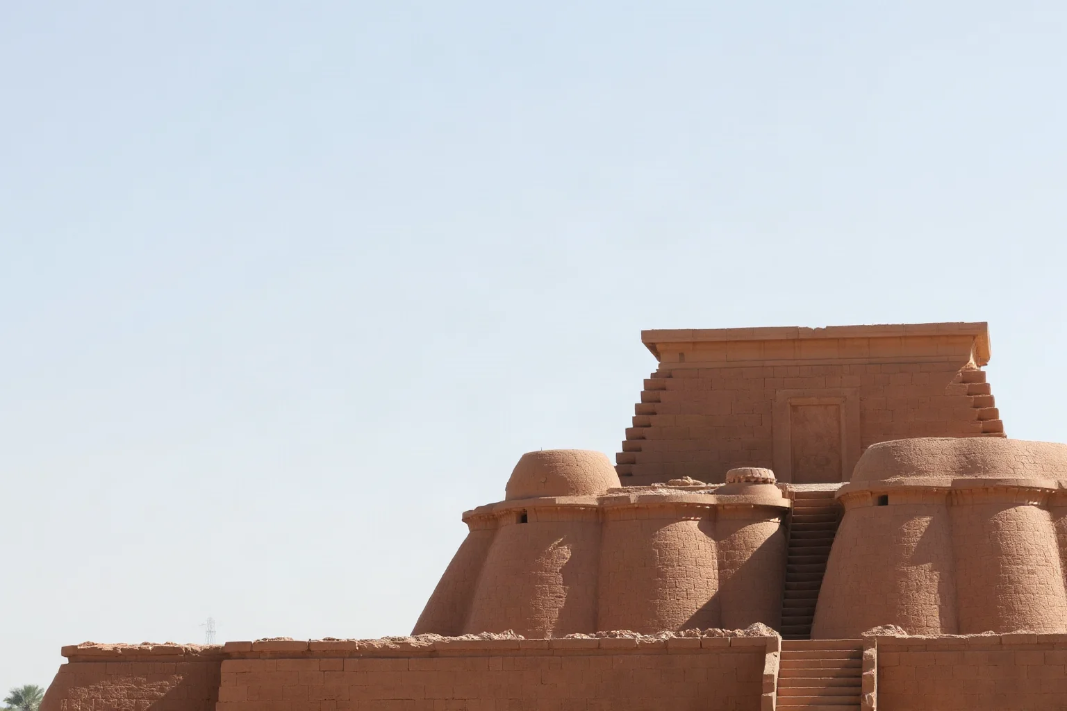 A massive stepped ancient temple structure made of mud brick rising against a clear Middle Eastern sky