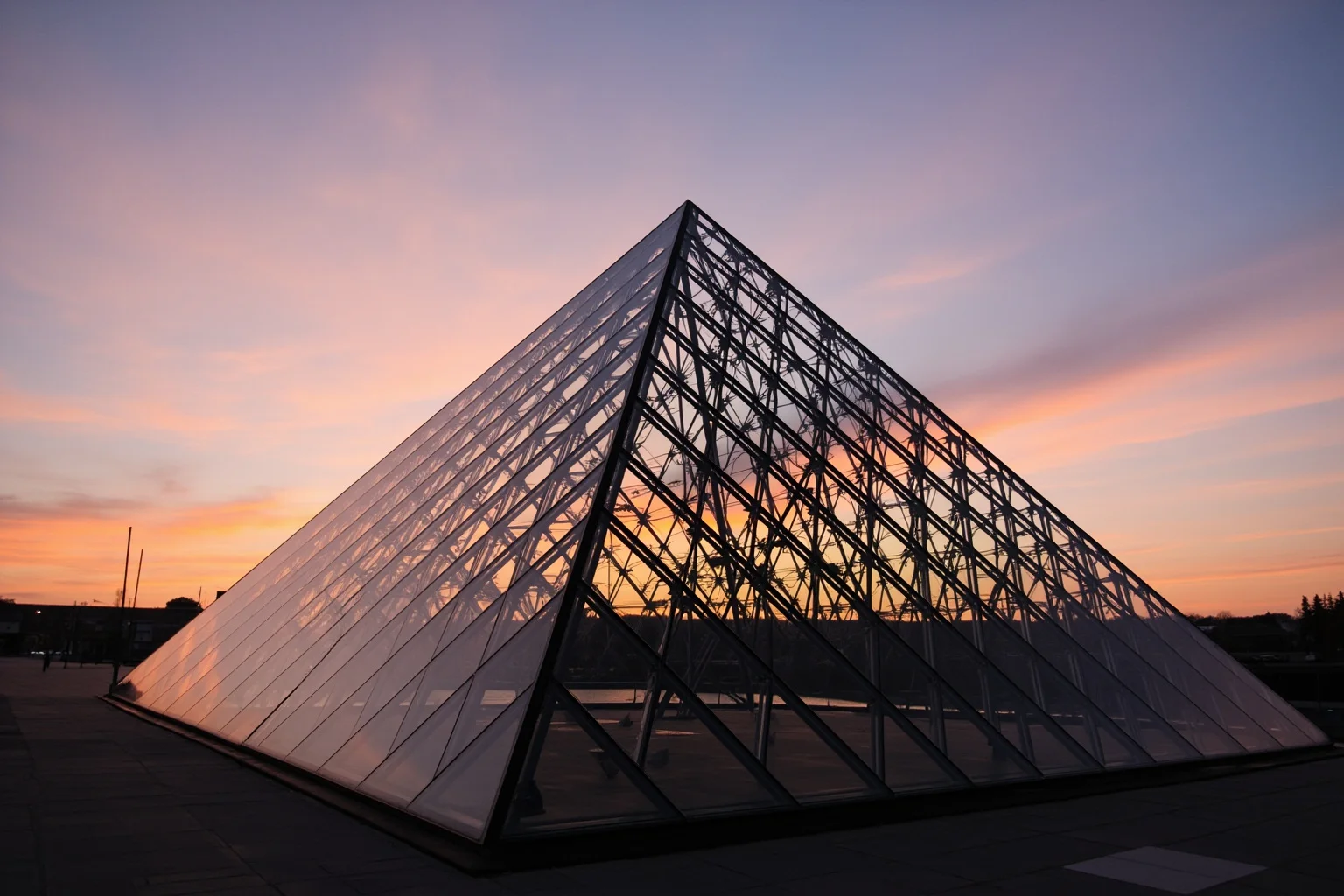 A modern glass pyramid structure at sunset, representing contemporary architecture and iconic building design