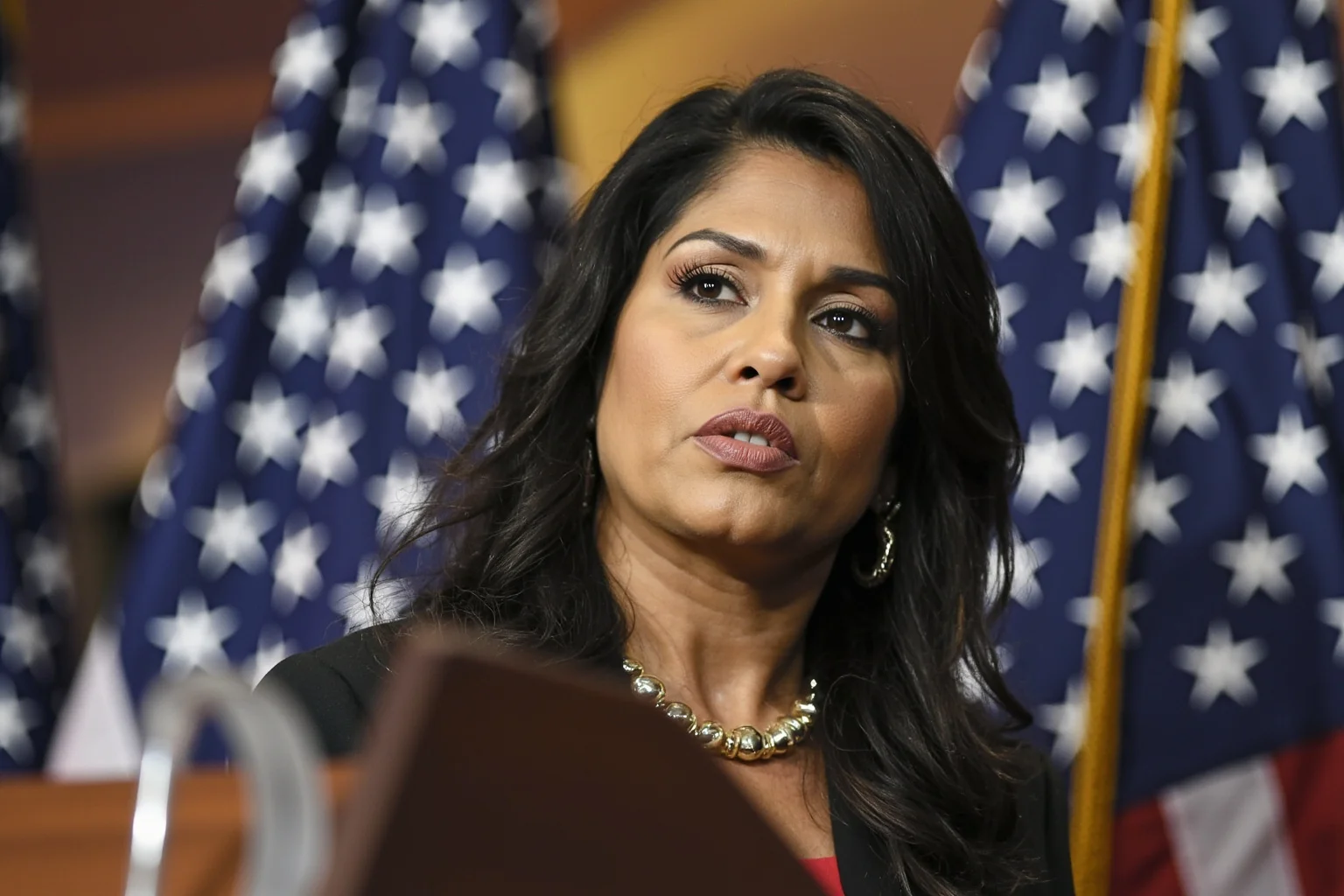 22 Inspiring Stories From Native American History 23 A modern Native American woman in professional attire standing at a podium with government seals nearby