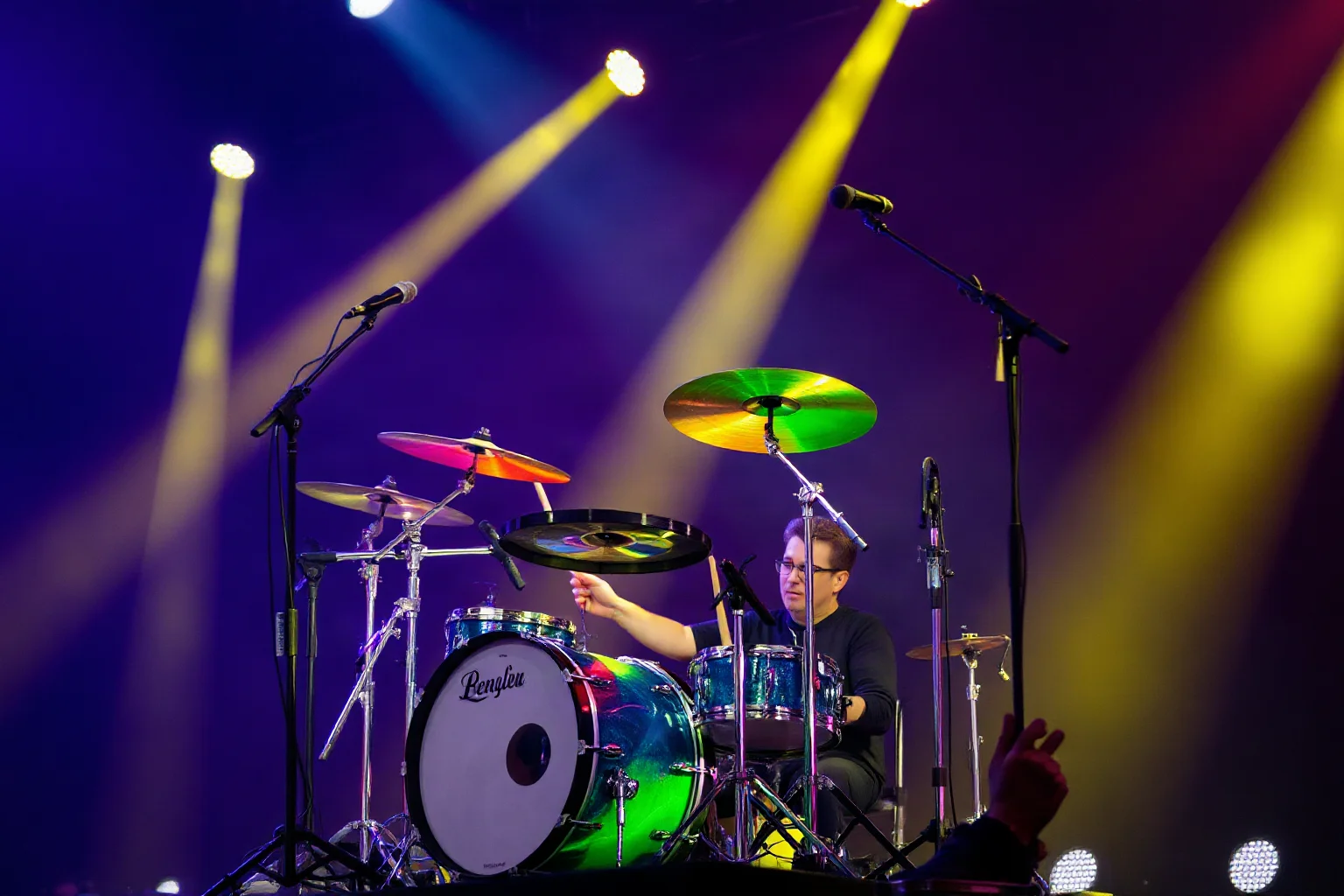 A new wave drummer with a lean kit performing with syncopated, energetic motion under colorful stage lights
