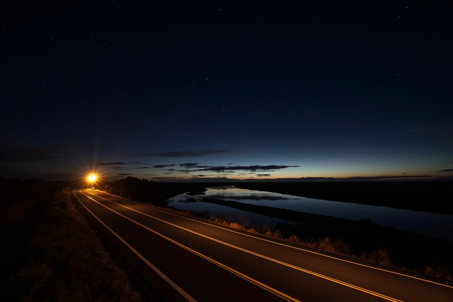 A nighttime irrigation canal along a rural road in northern Mexico, with sparse vegetation and dramatic lighting