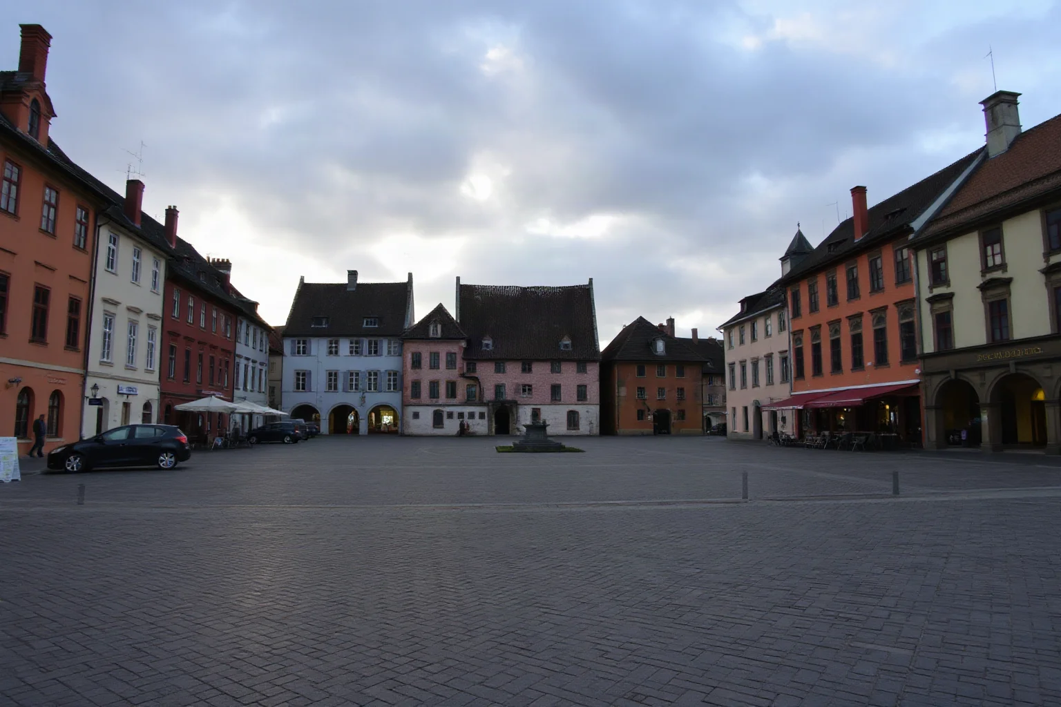A quiet medieval town square at dawn, empty streets, calm after a storm, muted colors