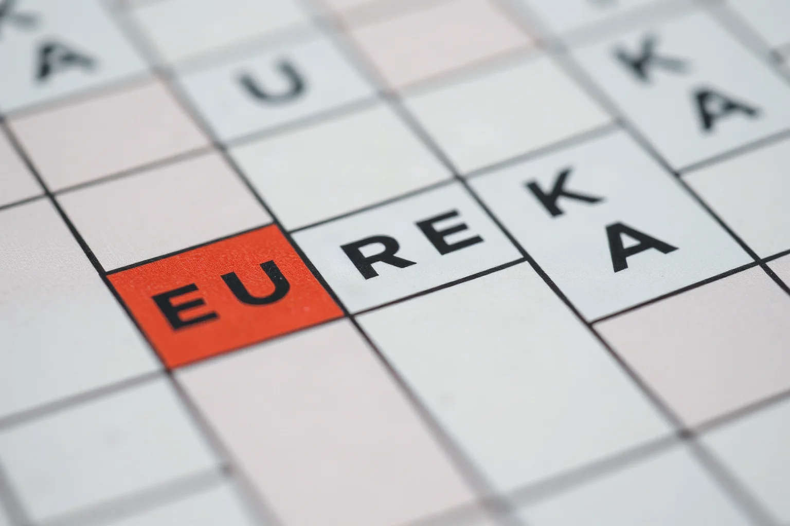 A retro newspaper or crossword puzzle close-up with the word EUREKA highlighted among the grid squares