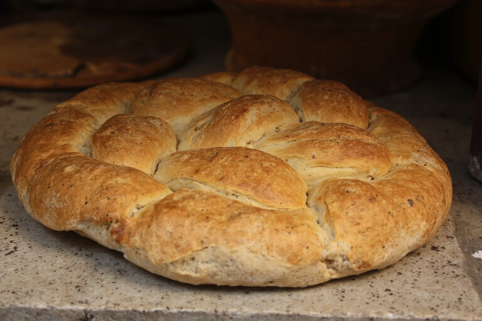 Ancient Greek Diet: 20 Foods Ancient Greeks Ate on a Daily Basis 3 A round loaf of golden wheat bread on a stone counter in an ancient Greek marketplace stall
