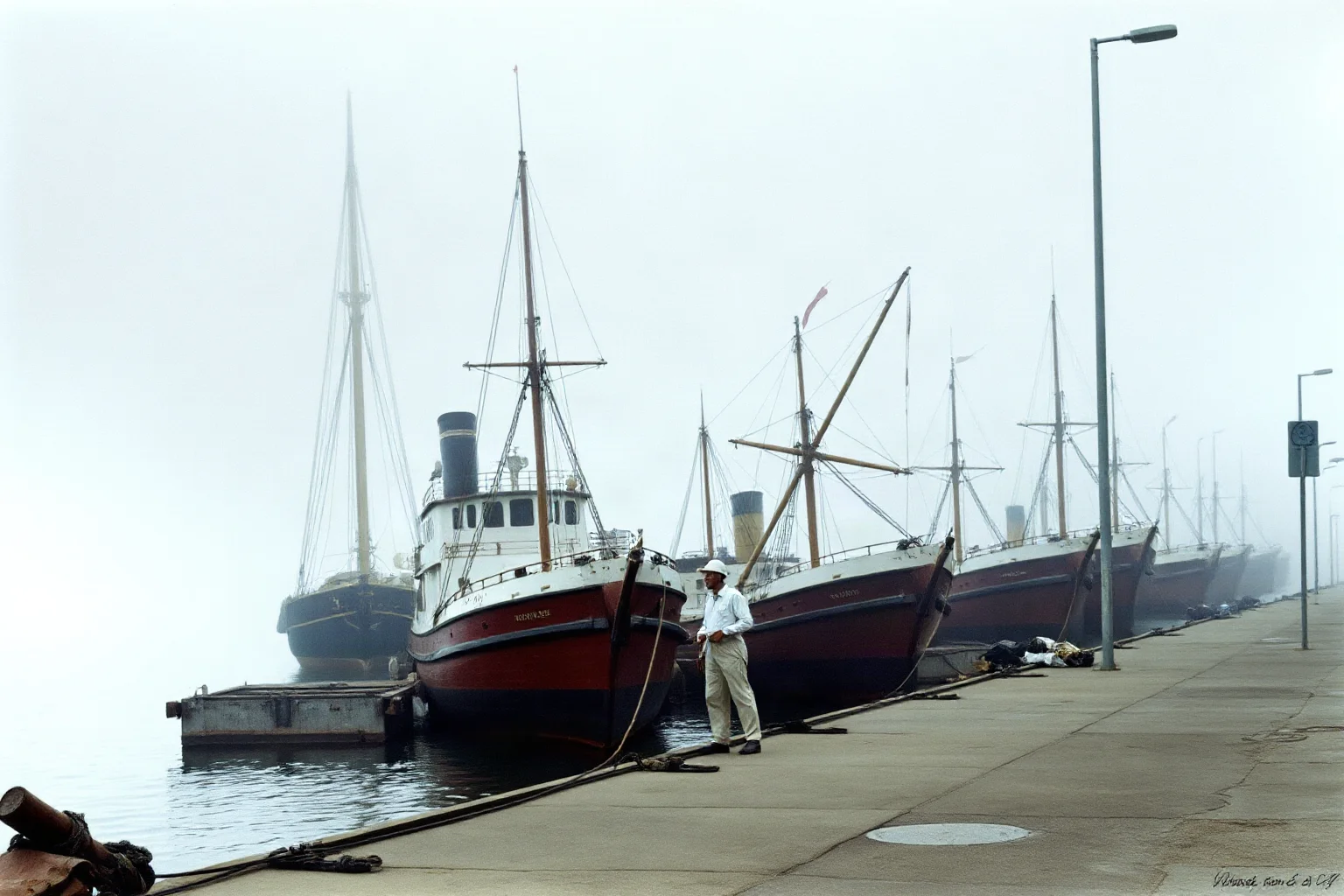 A row of merchant ships tied up idle at a foggy harbor dock, symbolizing a trade embargo, historical illustration