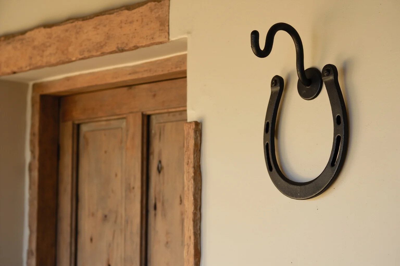 A rustic iron horseshoe hanging above a wooden farmhouse door