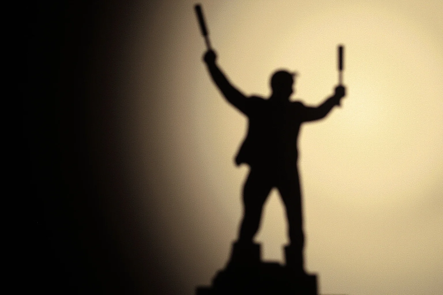 A shadowy figure holding a baton standing over a seated figure, representing escalating authority and control