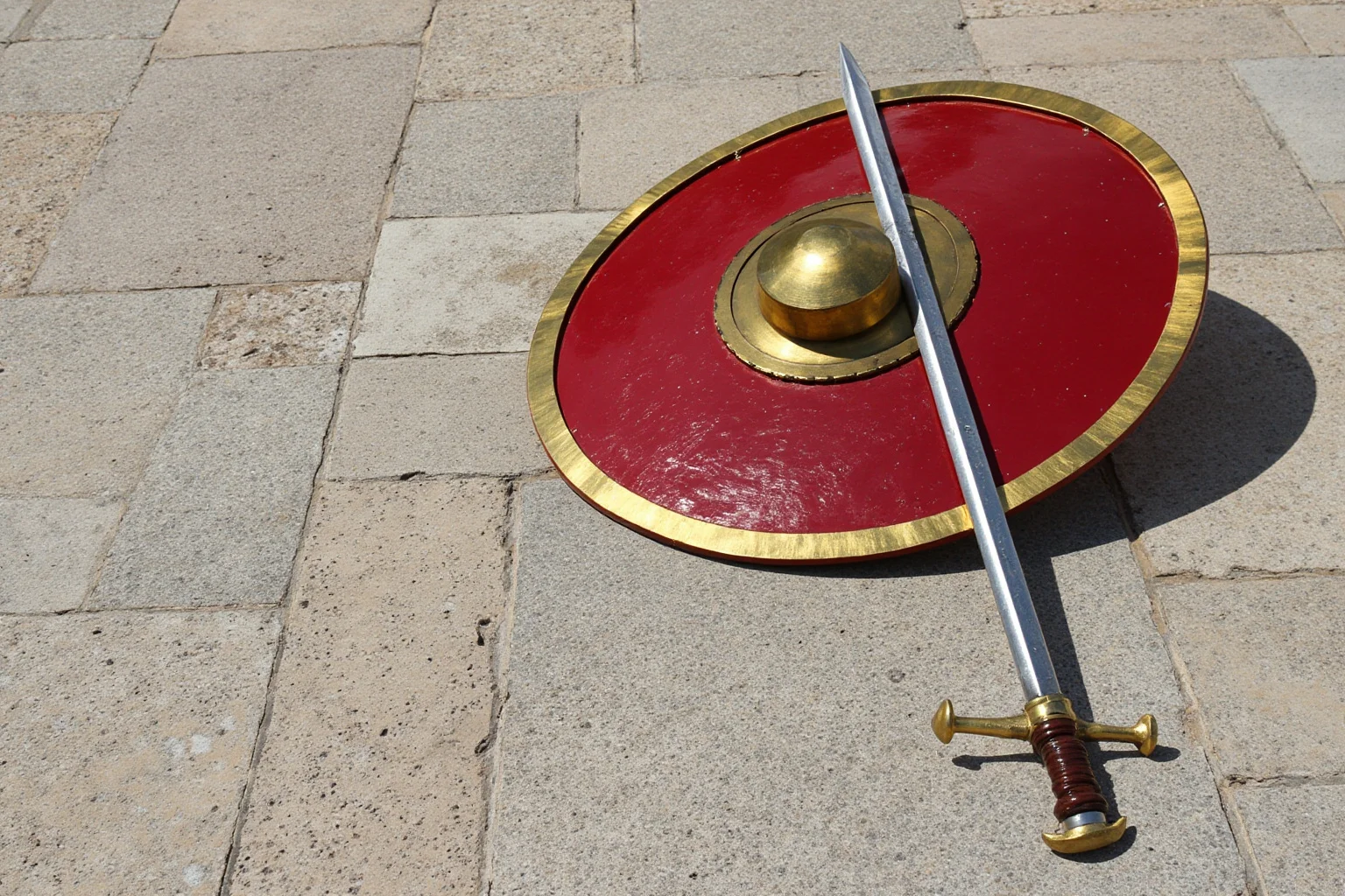 A short, sturdy Roman soldier's sword and shield arranged on a stone military parade ground