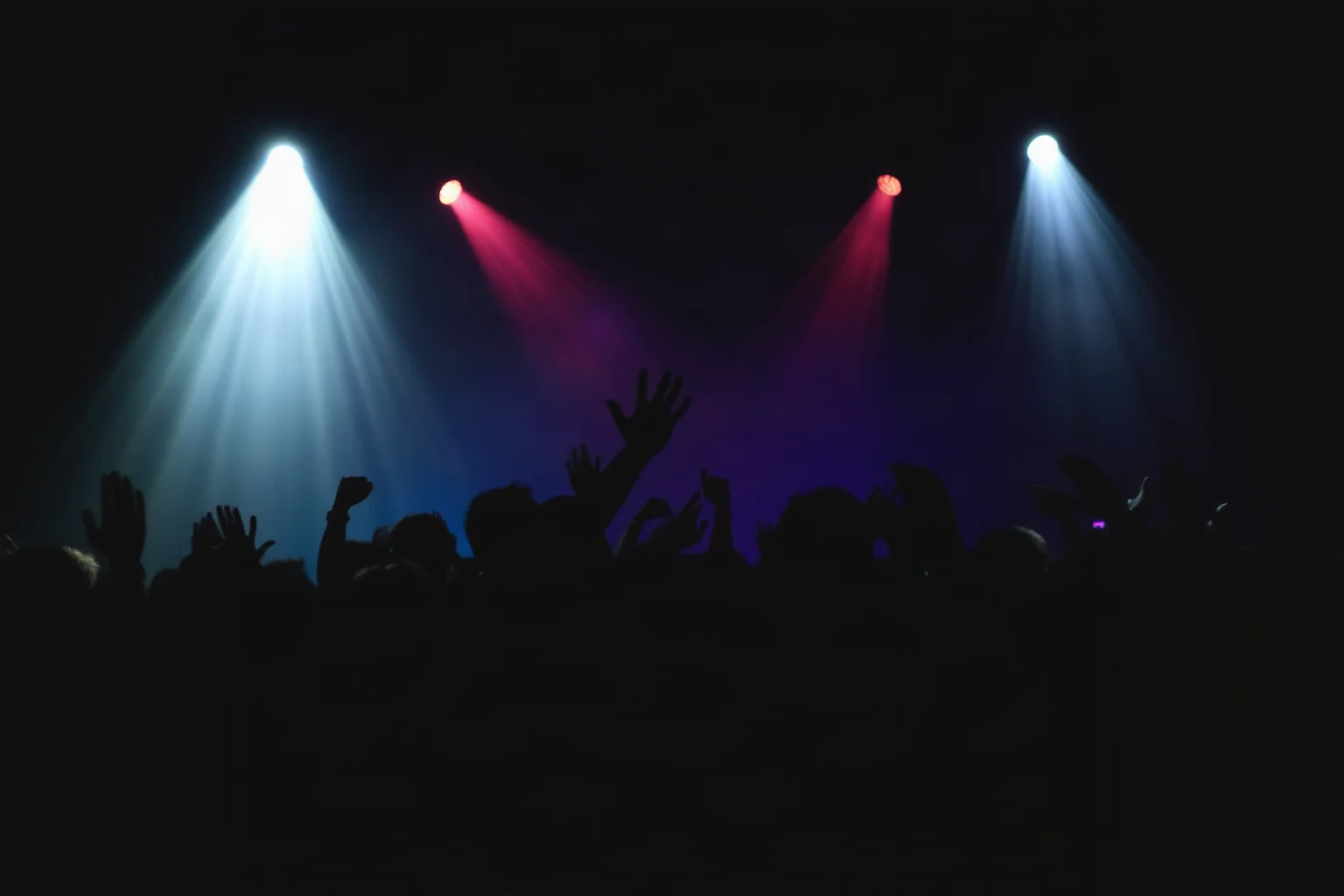 A silhouette of a crowd dancing under dramatic stage lighting, symbolizing crowd psychology and collective behavior