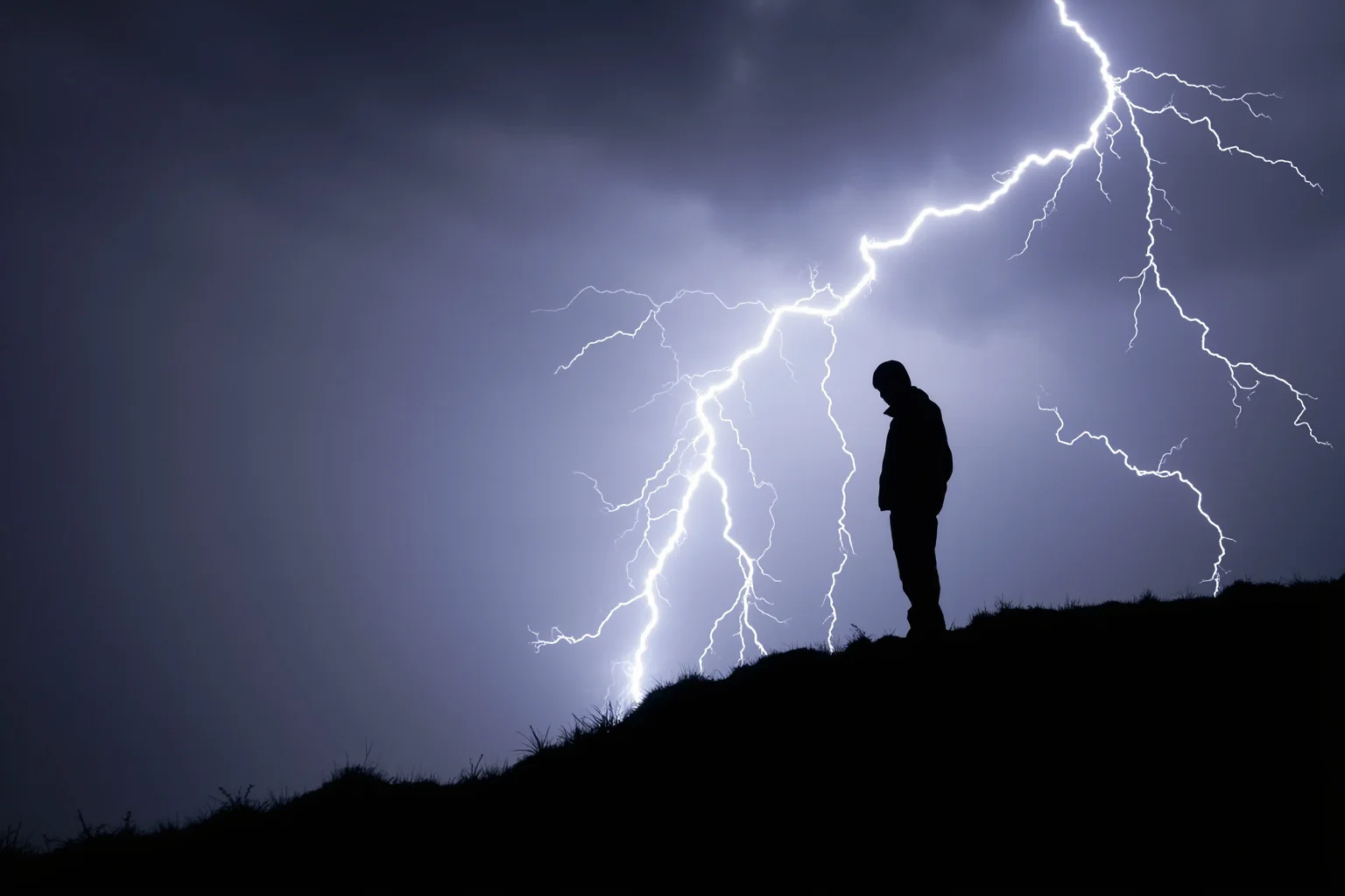 The Human Lightning Rod: The Man Who Was Struck Seven Times 12 A silhouette of a person standing on an open ridge during a thunderstorm, illustrating lightning exposure risk