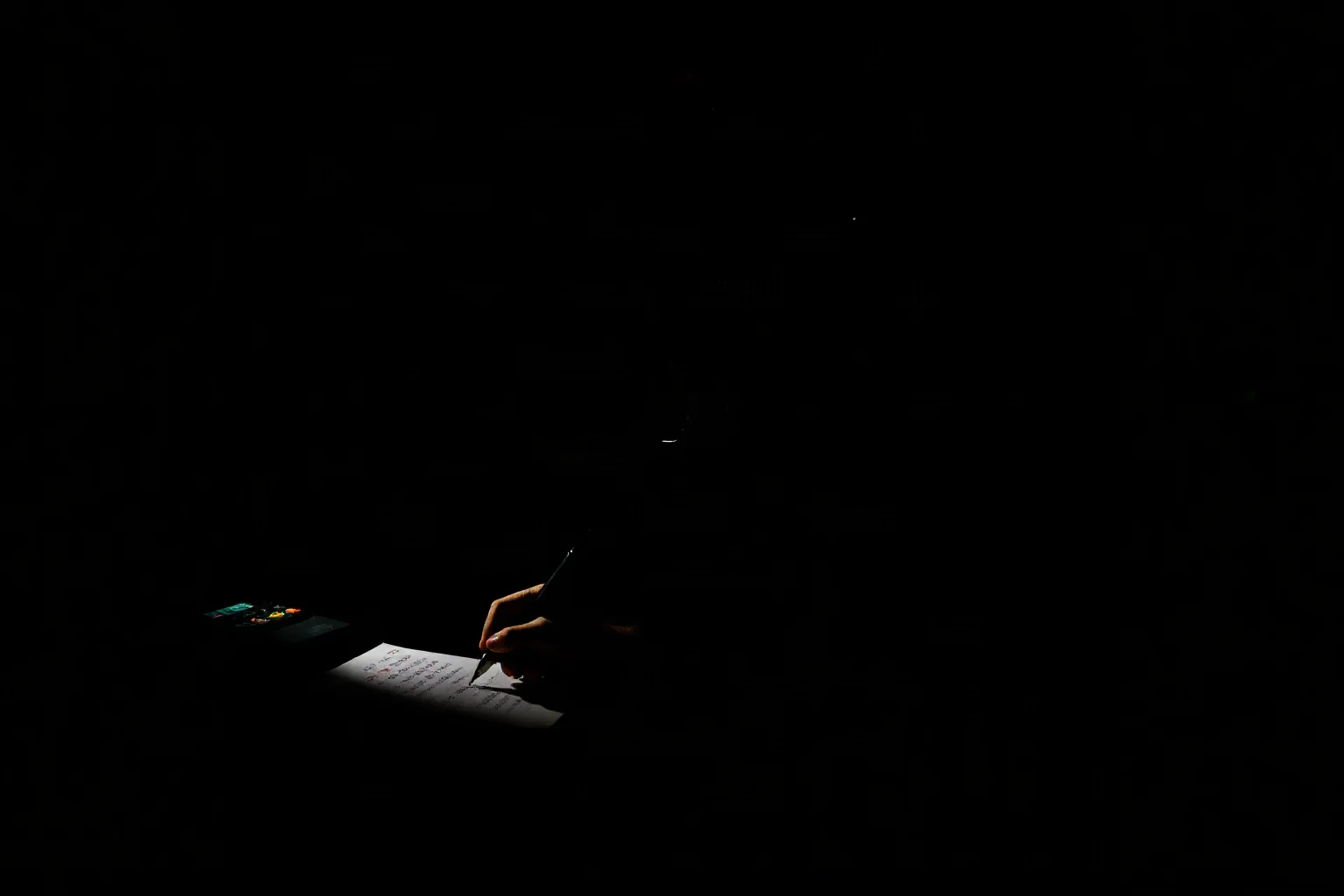 A silhouette of a person wearing headphones at a radio desk, writing down groups of numbers on paper