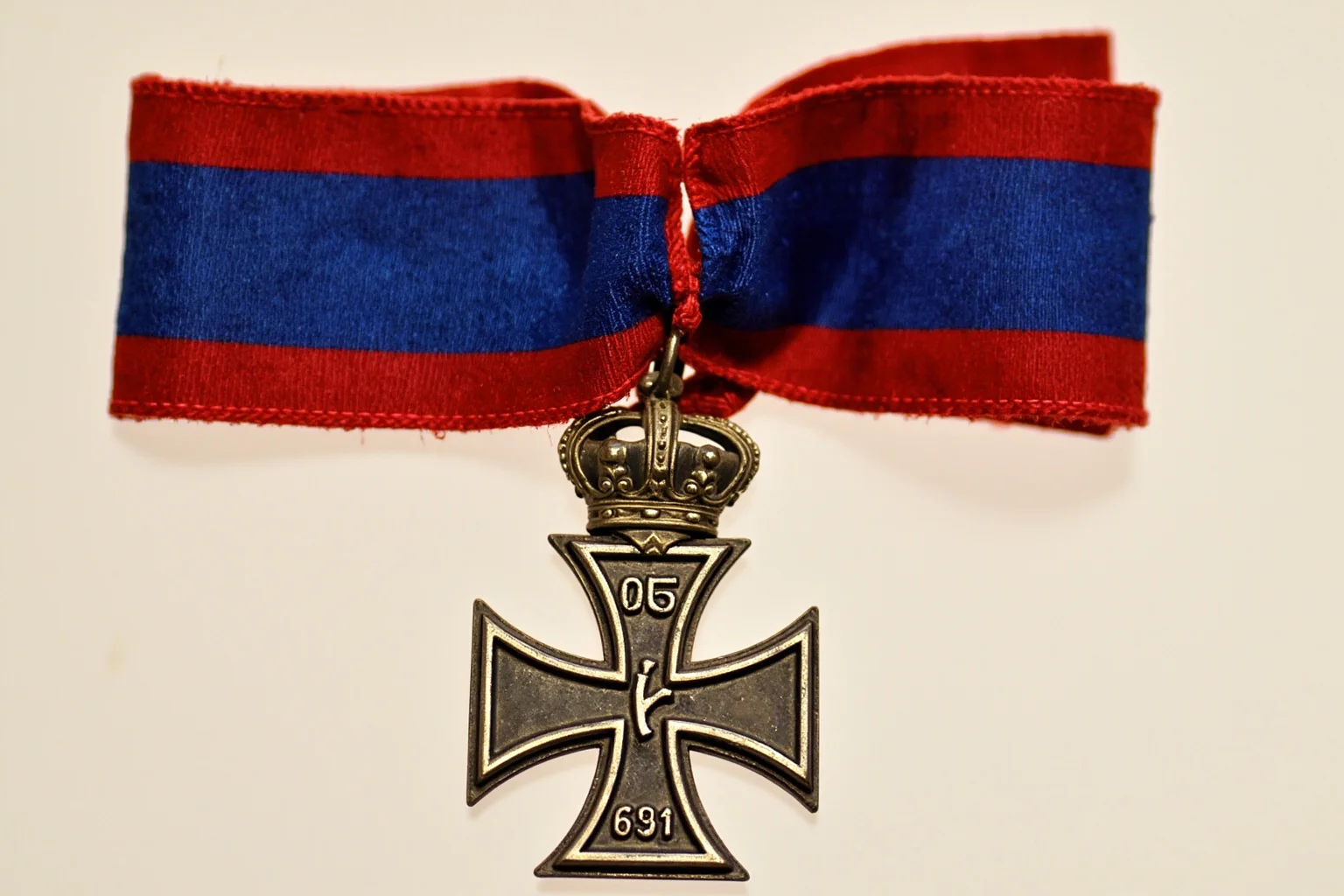 Highest Military Decorations: 20 Rare and Obsolete Medals You'll Never See Again 18 A silver cross medal on a red-and-blue ribbon with a small crown detail, symbolizing a leadership-focused military honor