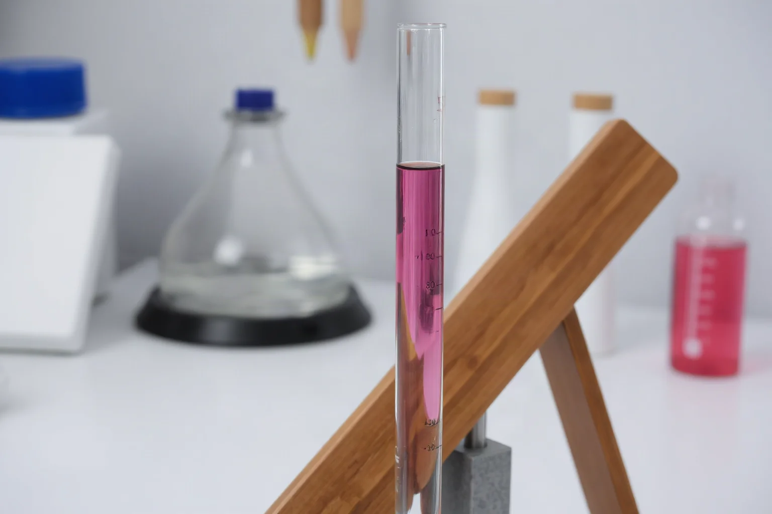 A simple glass thermoscope tube with colored liquid on a wooden stand in a study