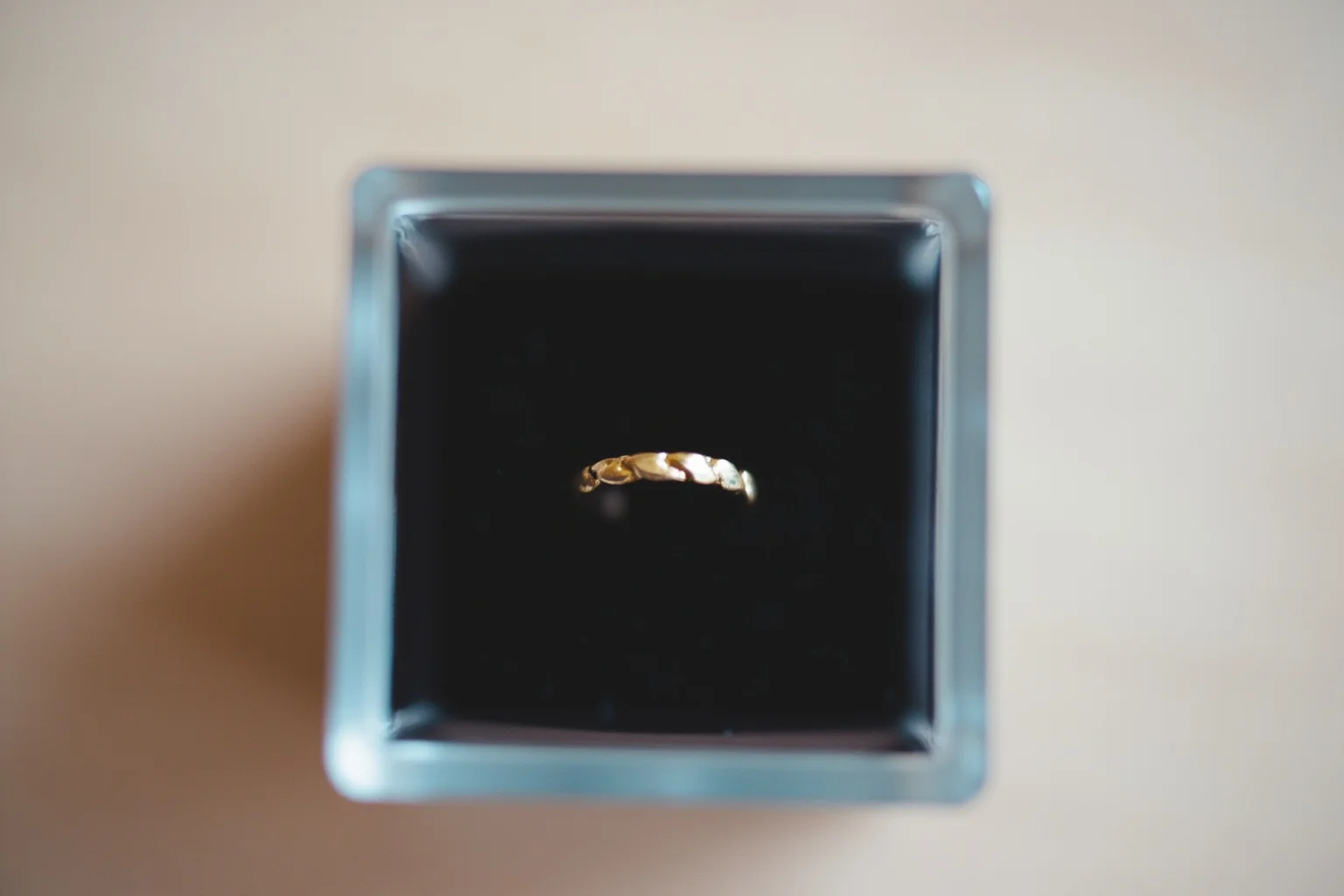 A simple gold wedding ring resting on black velvet inside a small display case