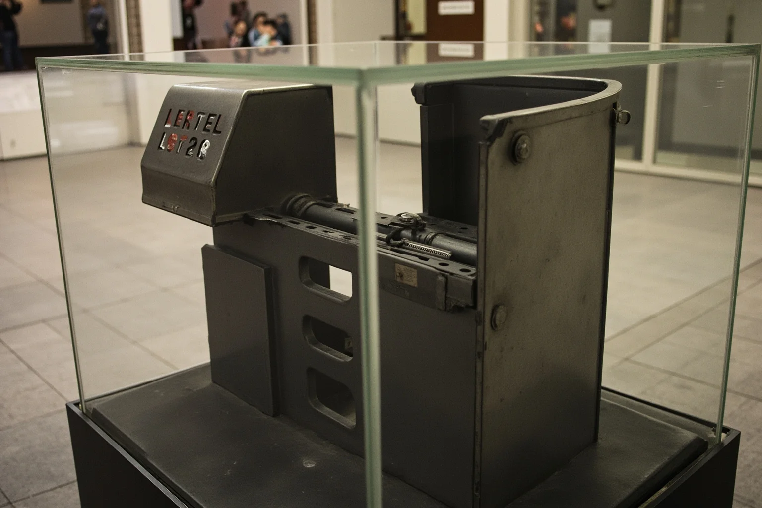 A single mangled metal subway turnstile displayed in a glass museum case