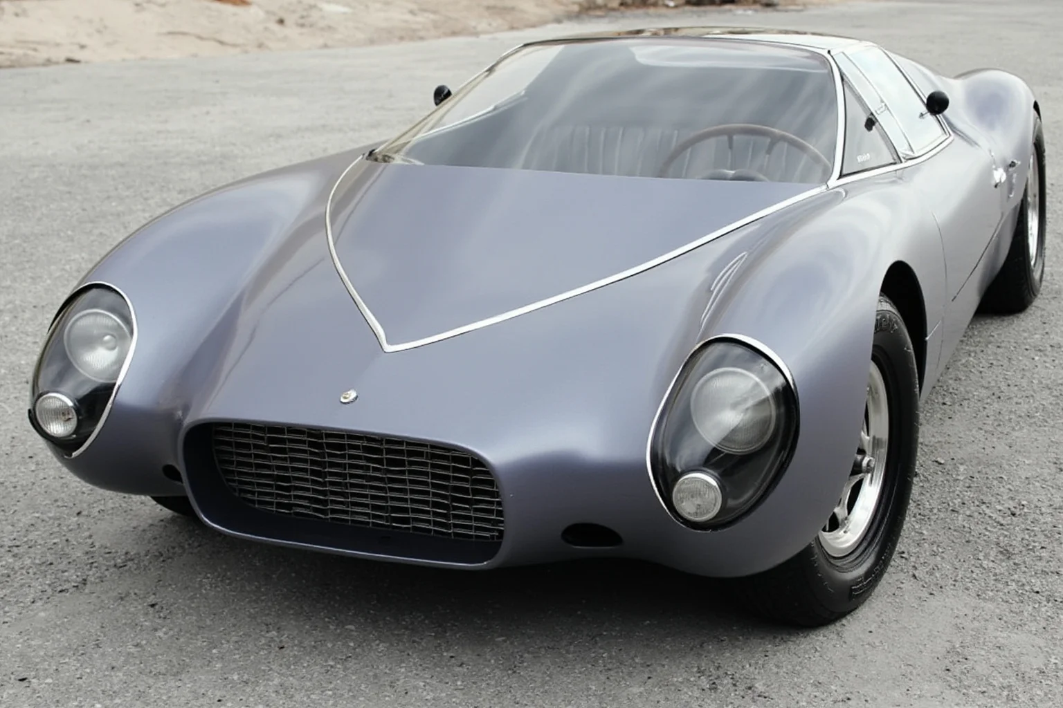 A sleek fiberglass-bodied 1960s sports coupe with a wraparound windshield and minimalist grille