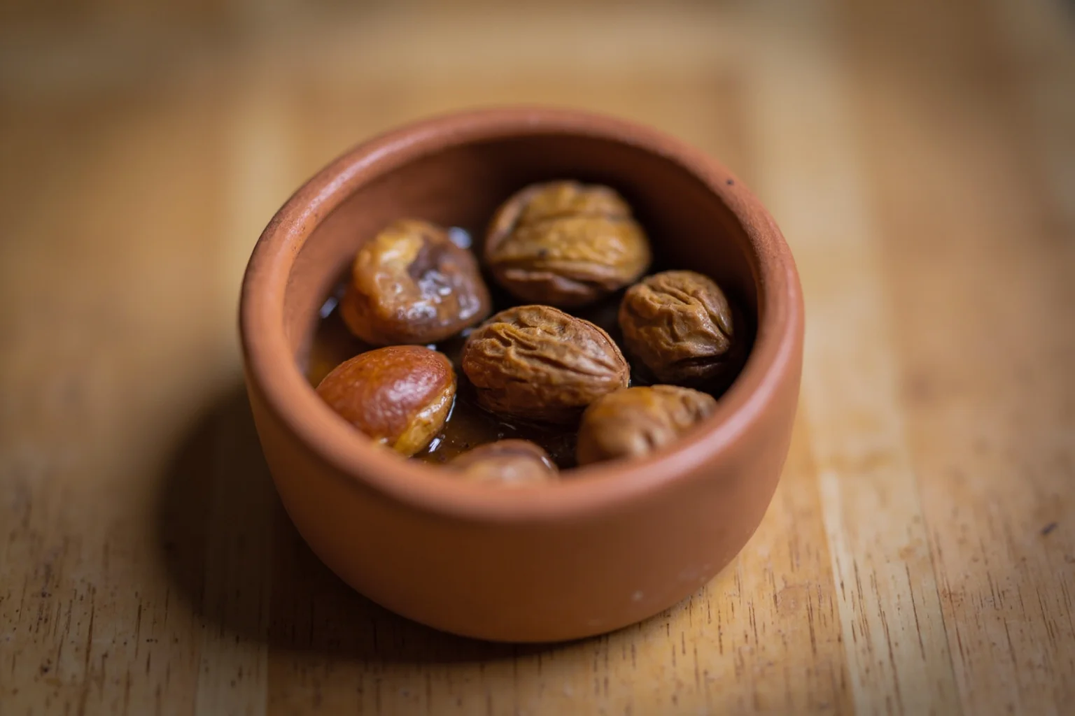 Ancient Greek Diet: 20 Foods Ancient Greeks Ate on a Daily Basis 15 A small clay dish filled with almonds, walnuts, and chestnuts on a wooden surface