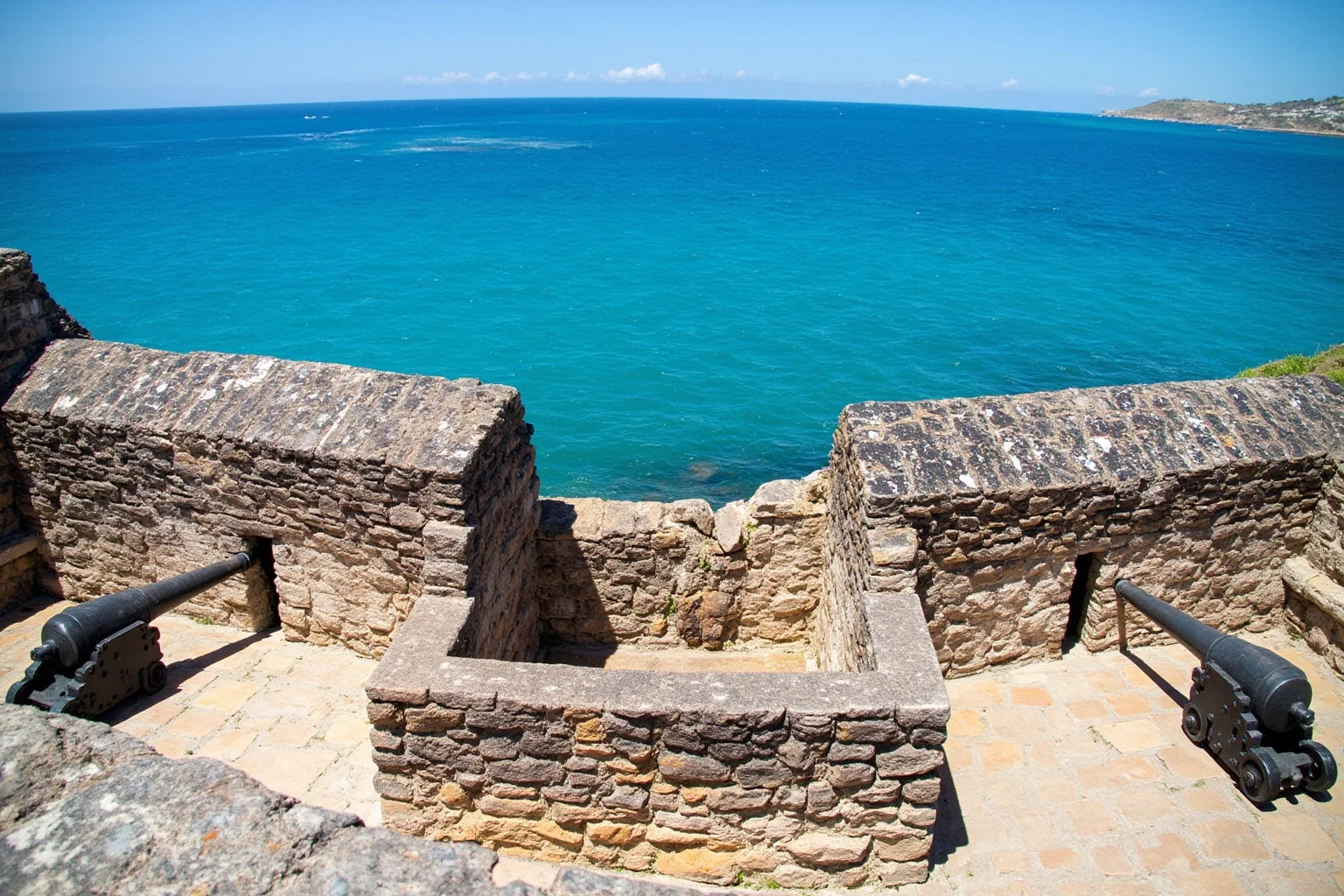 A Spanish colonial coastal fort with thick stone walls and cannon positions overlooking turquoise water