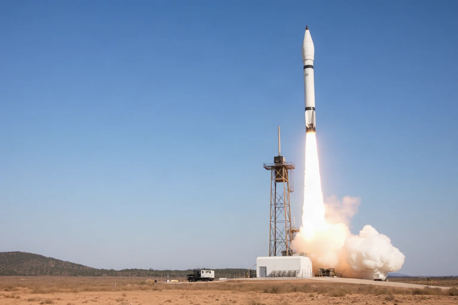 A tall cylindrical rocket on a launch stand in a barren field, evoking early missile and space technology