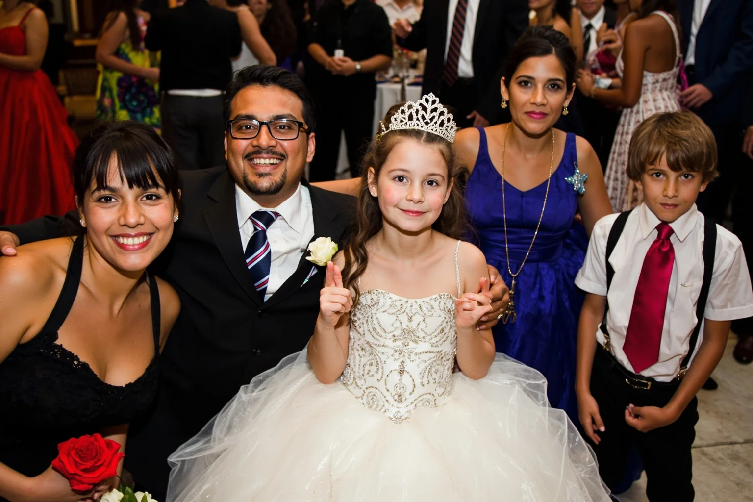 A teenage girl in an elaborate formal gown celebrating with family at a festive Latin American party