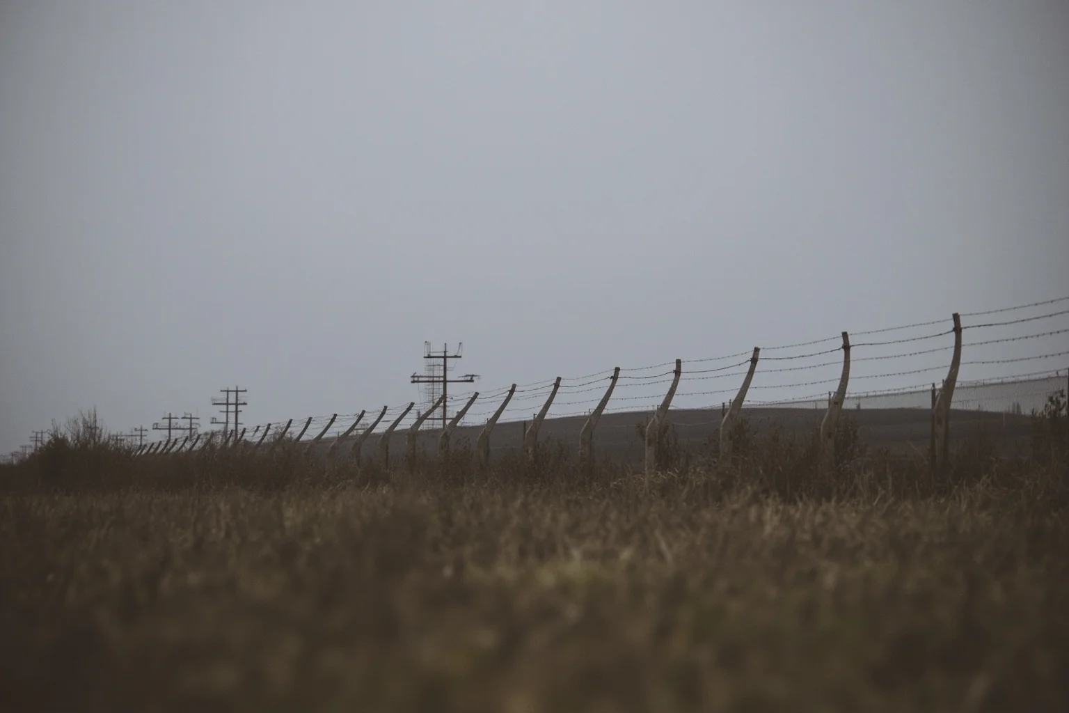 Wars That Lasted A Lot Longer Than You Thought 11 A tense fortified border with barbed wire and watchtowers under a gray sky, symbolizing an unresolved armistice