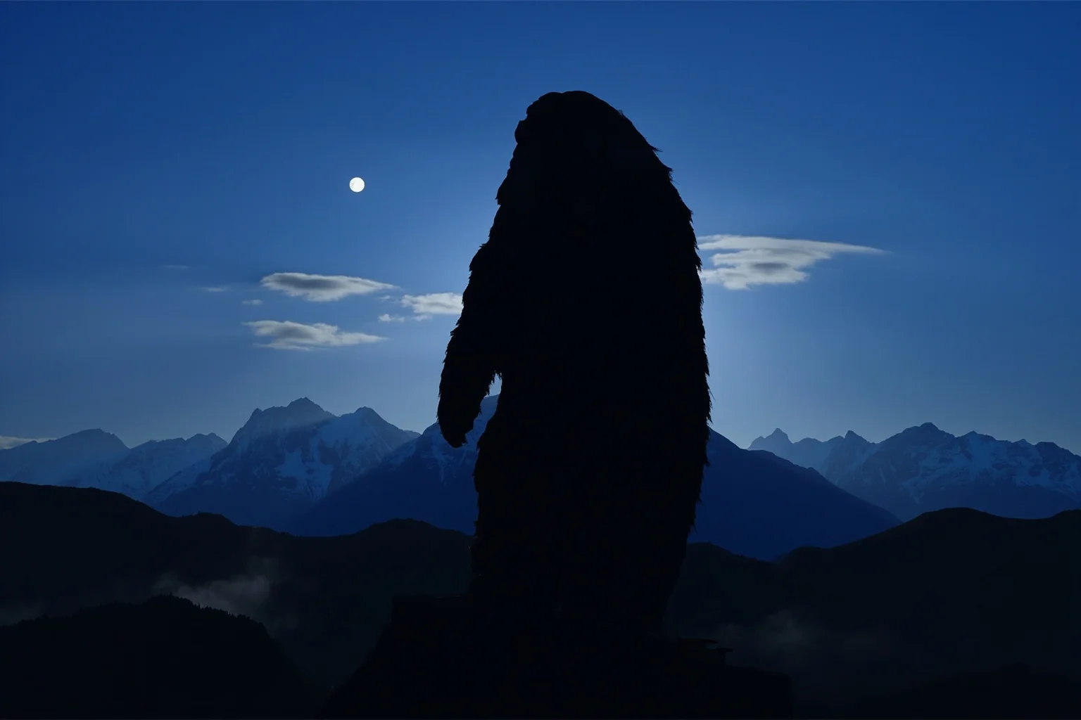A towering Himalayan yeti silhouette against snowy mountain peaks under moonlight