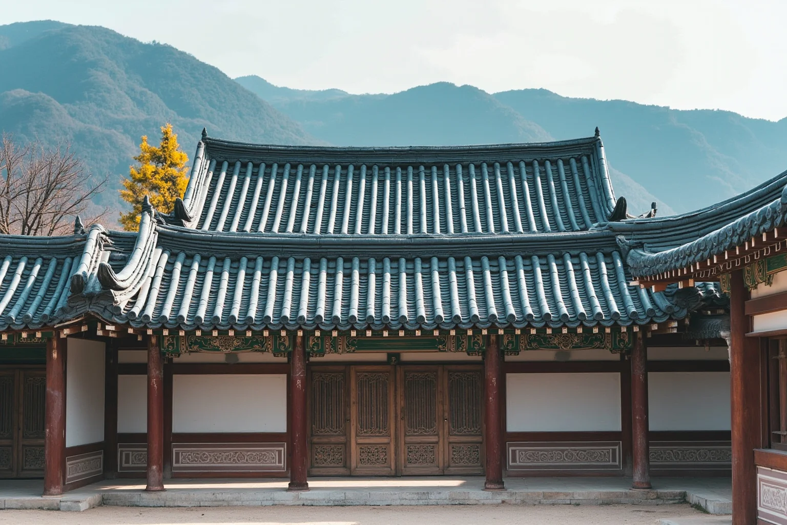 A traditional Korean palace hall with sweeping tiled roofs and mountains behind