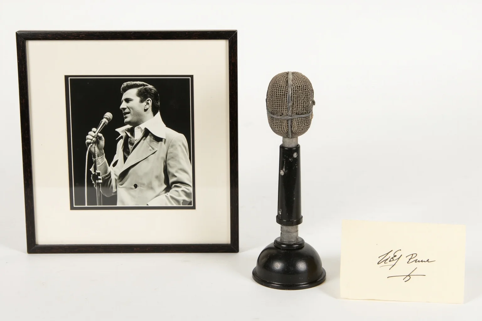 A vintage 1950s microphone and framed black-and-white concert photograph with a signed autograph card beside it