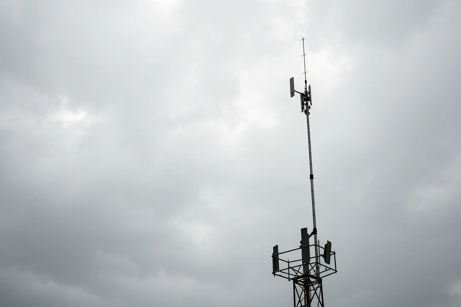 A weathered antenna tower against a cloudy sky, suggesting a remote clandestine radio transmitter site