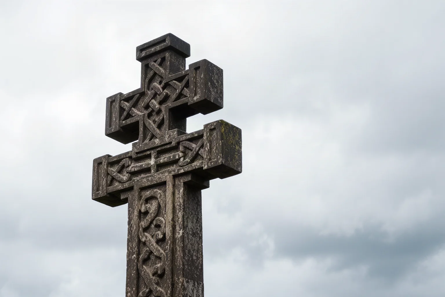 A weathered stone Celtic cross under a cloudy sky, symbolizing a saint's uncertain death date