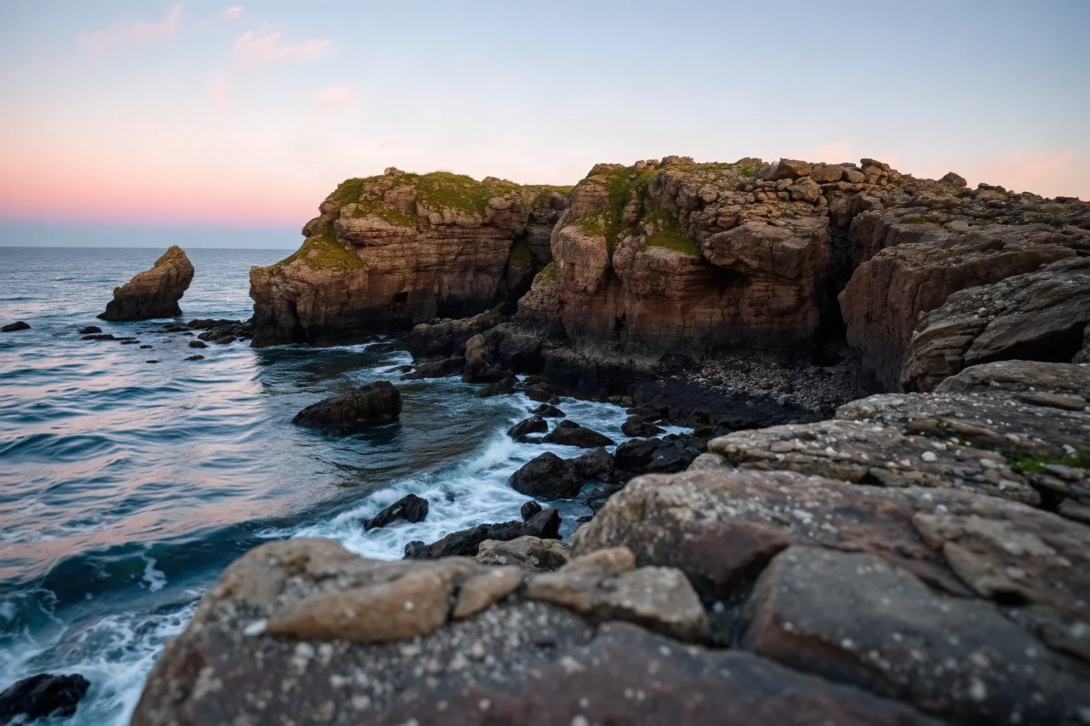 A weathered stone coastline in Britain at dusk, evoking a Romano-British homeland of the 5th century