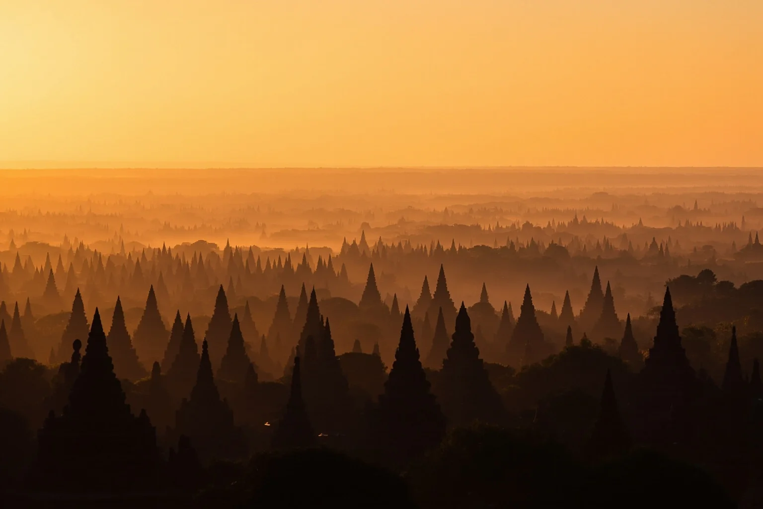 A wide plain dotted with hundreds of ancient brick temple spires at sunset